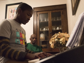 In their dining room, Tamba watches his son play piano which he has been practicing for years.